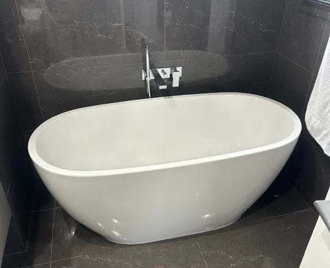 Freestanding stone bath in a renovated bathroom with floor-mounted filler tap