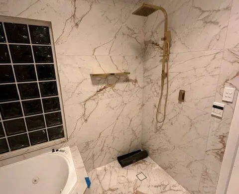 Marble-look shower with brushed brass shower rail and fixtures