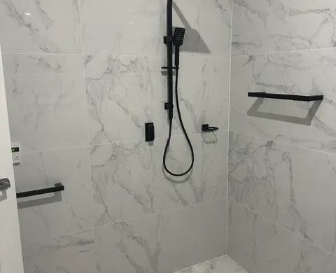 Marble-look walk-in shower with matte black rail shower and fixtures