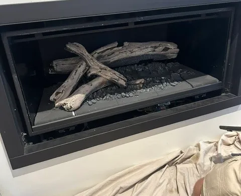 Modern black gas log fireplace insert set into a marble hearth