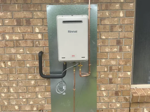 Continuous-flow gas hot water unit mounted on a brick exterior wall