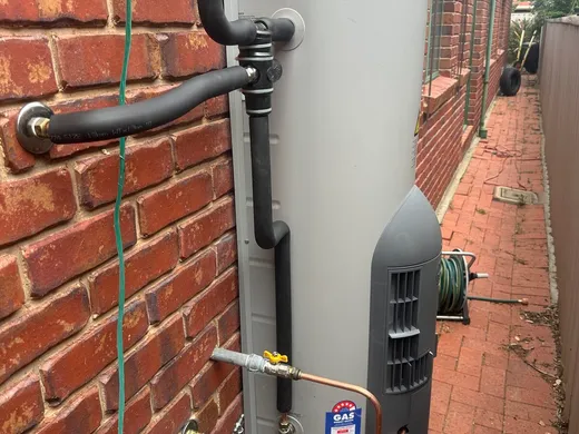 Storage hot water system neatly installed against a brick wall