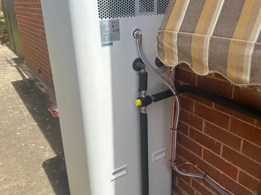 Tall storage hot water system installed against a brick wall
