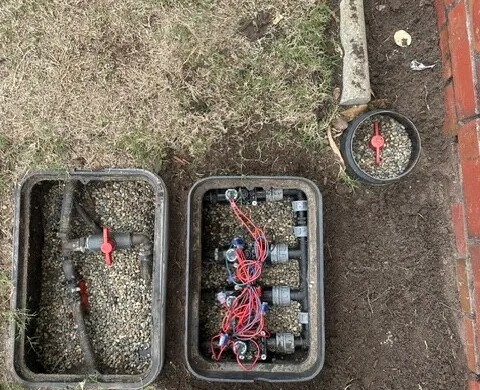 In-ground irrigation valve boxes installed along a garden edge